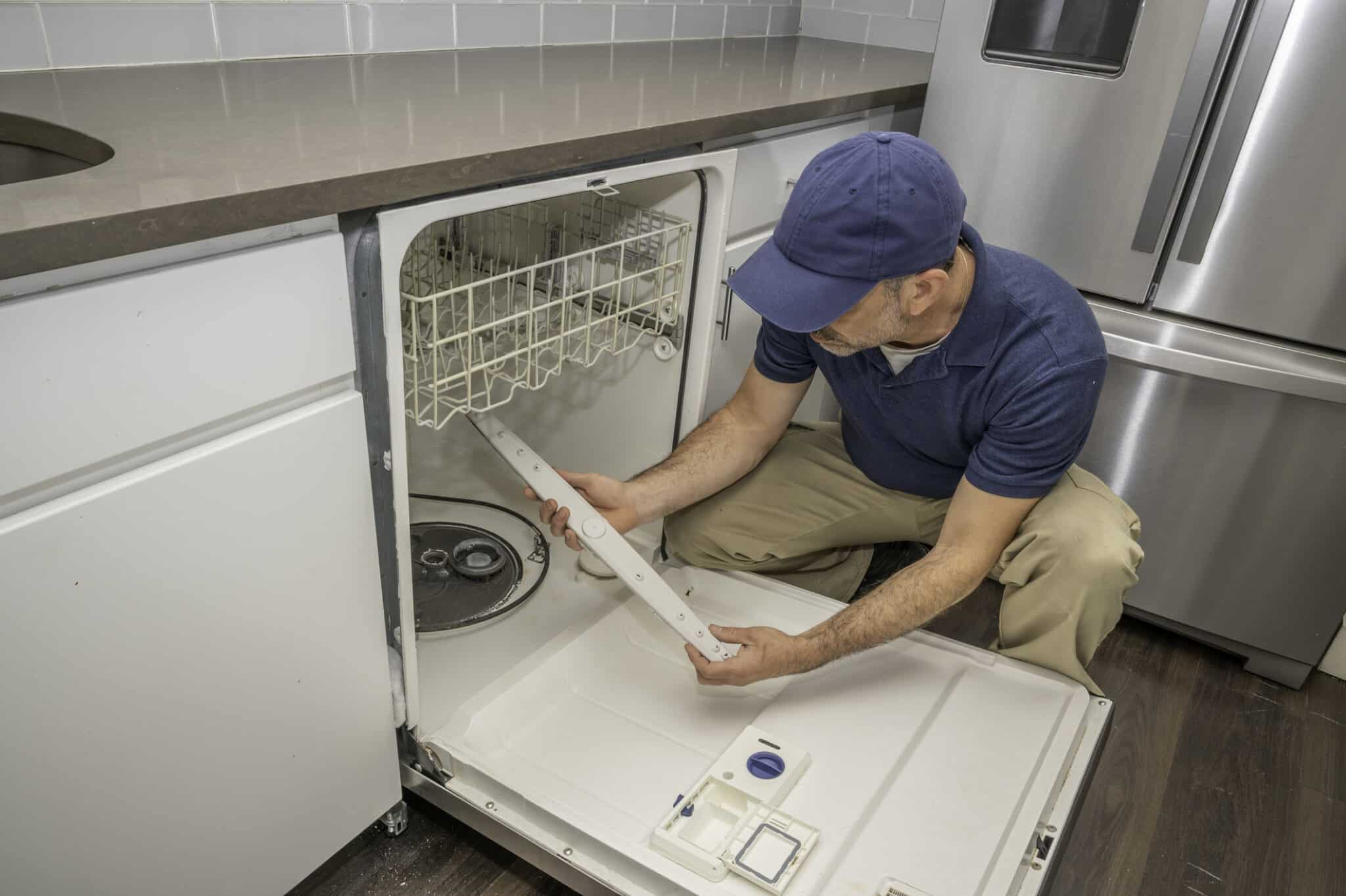 Plumbing tips repairman working on a broken dishwasher.